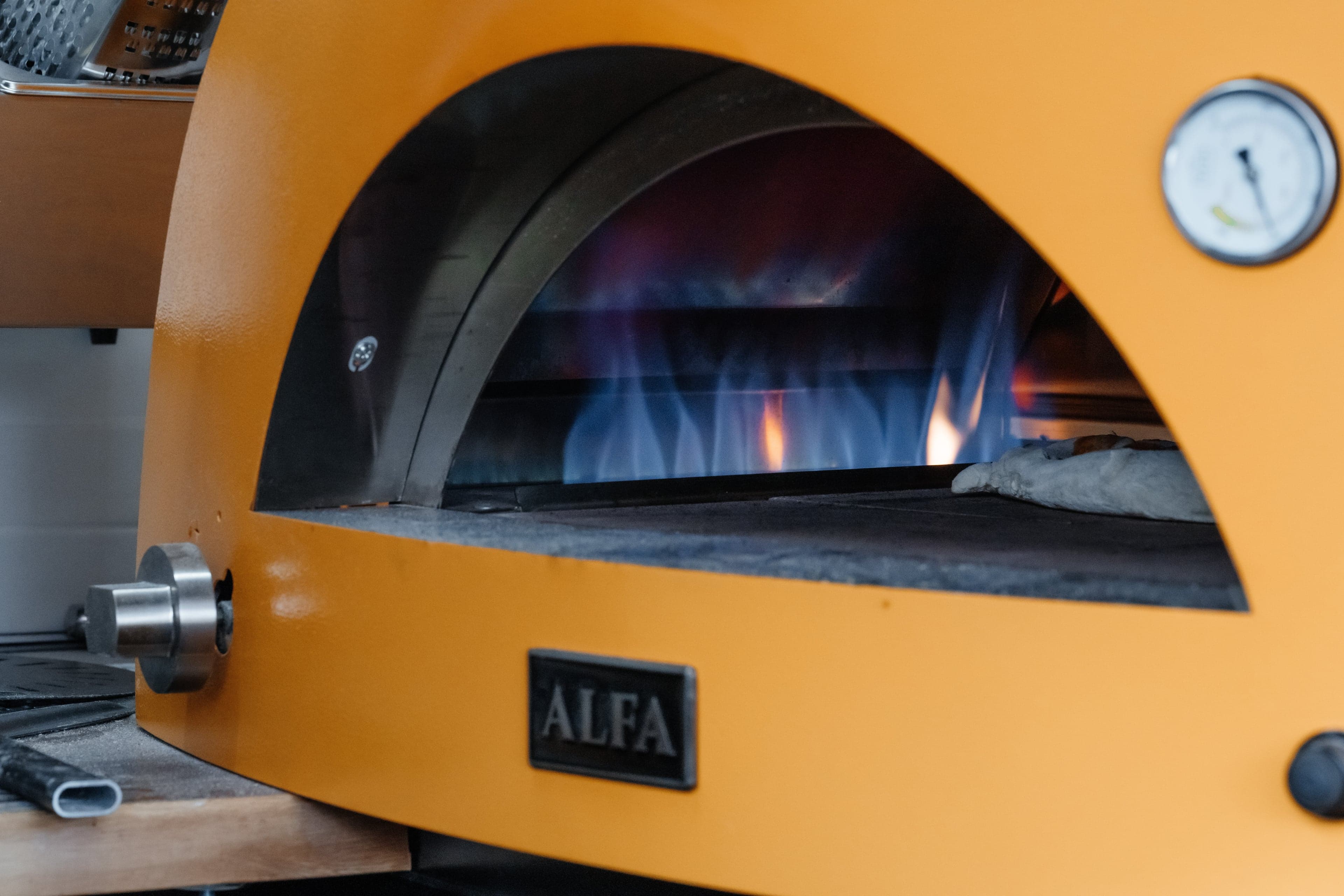 Pizza dough being shaped by hand before going into the wood-fired oven